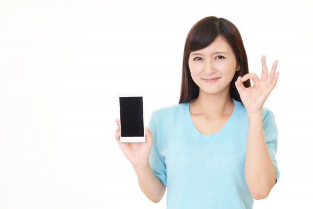 スマホを持ちokサインをする女性